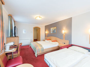 Two double beds are available in this room, a TV and many chairs are also in the room.