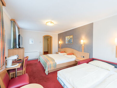 Two double beds are available in this room, a TV and many chairs are also in the room.