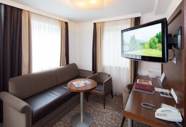 Couch mit kleinen Rundtisch und einen Fernseher an der Wand